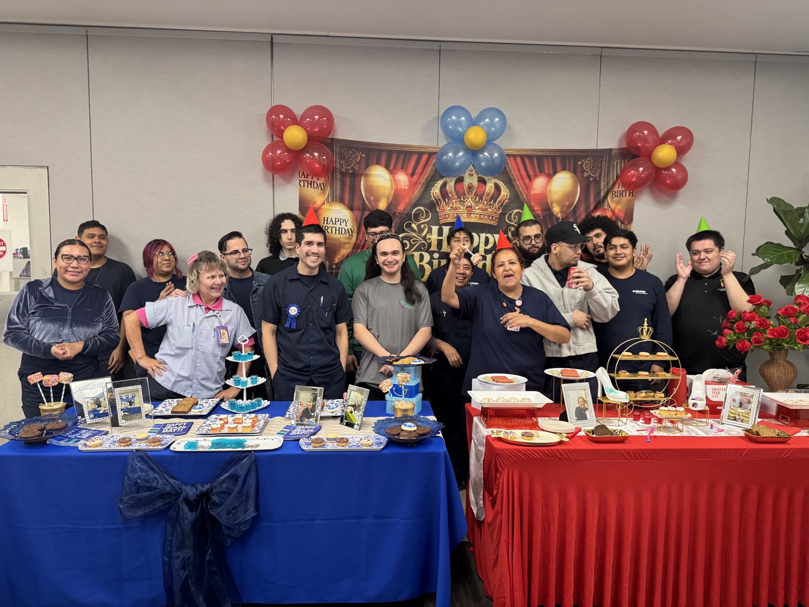 Big group of guests cheering behind birthday dessert tables