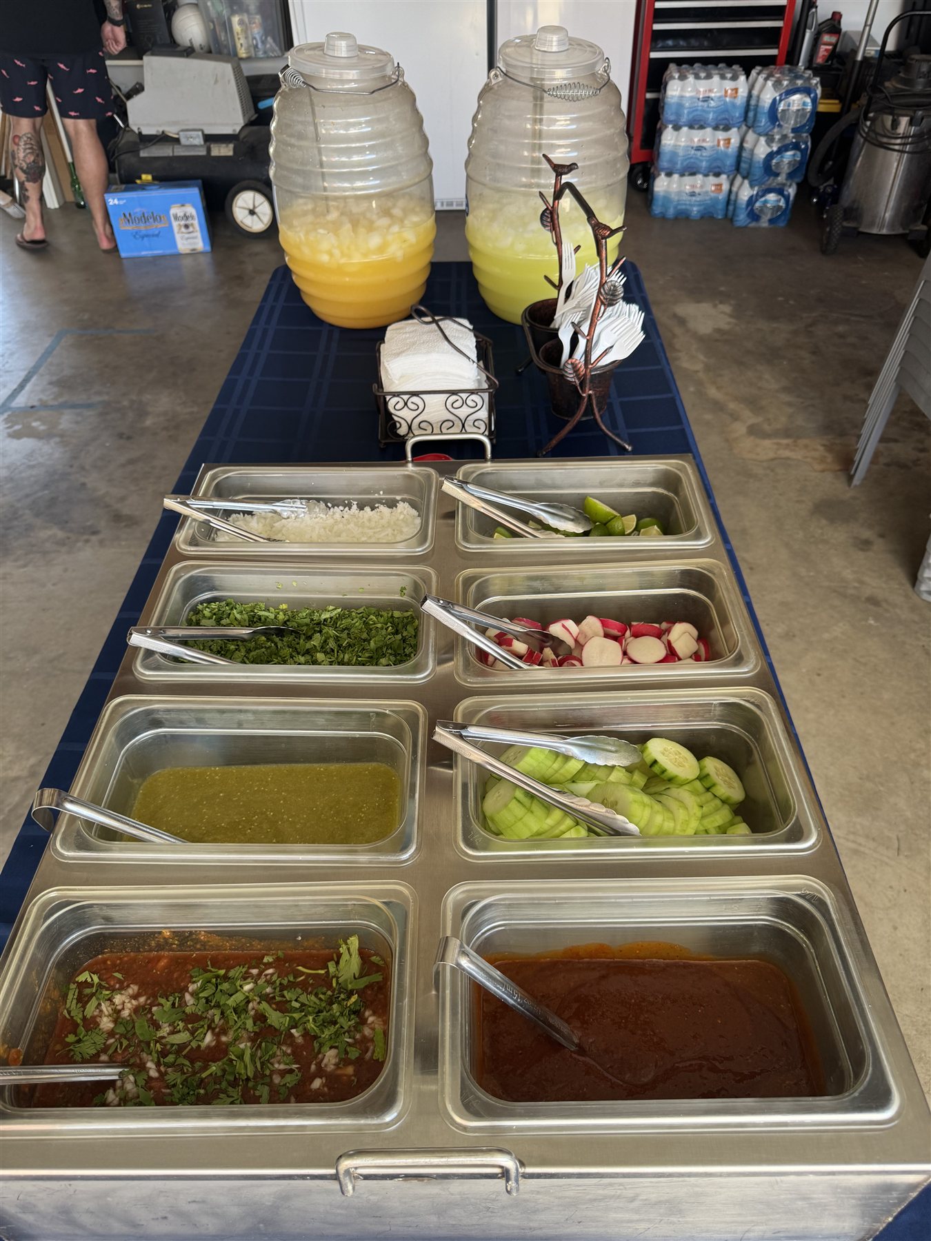 Self-serve salsa bar with fresh limes, radishes, cucumbers, salsa roja and verde, and aguas frescas