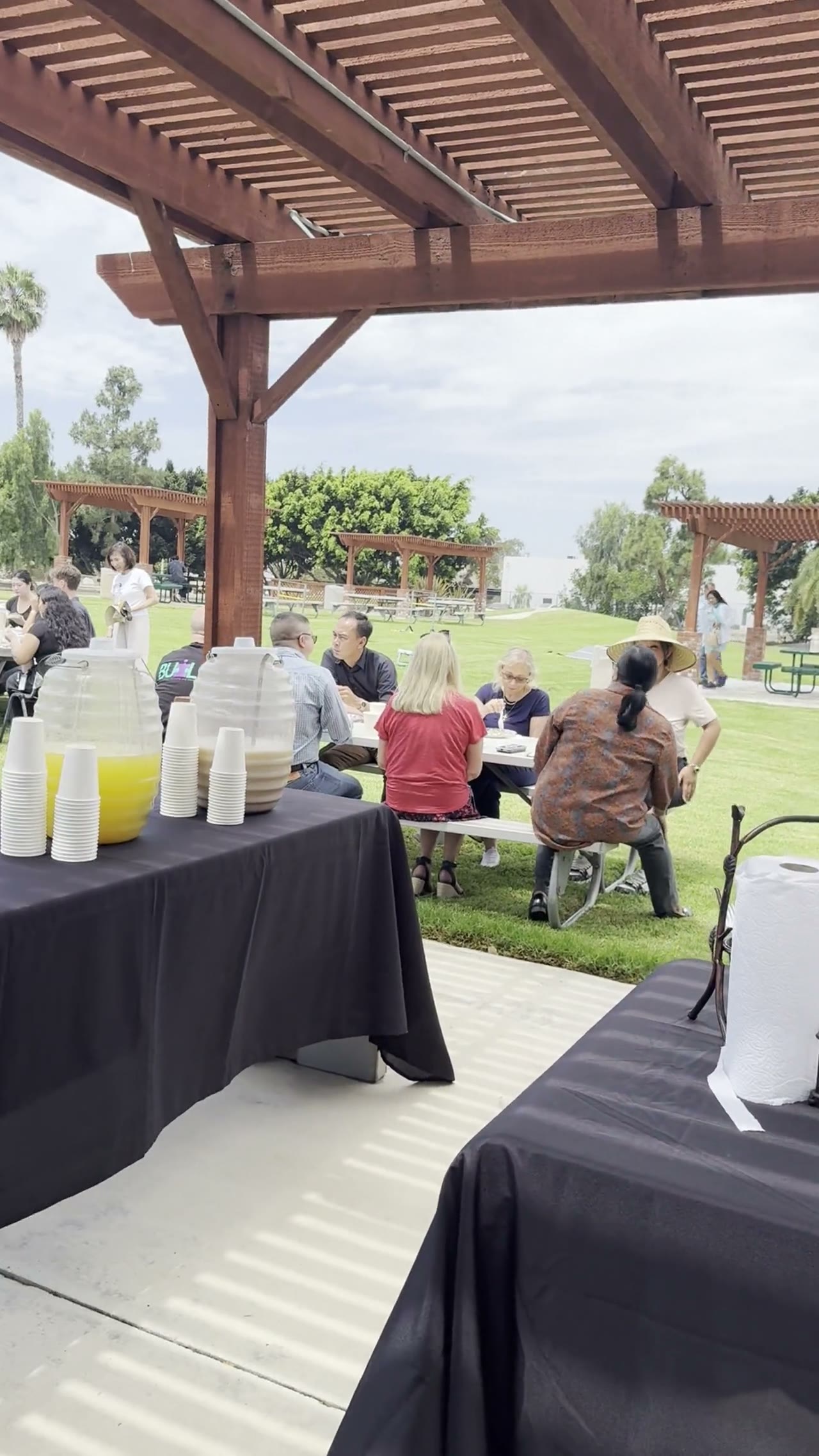 Guests at an outdoor catered event under a pergola